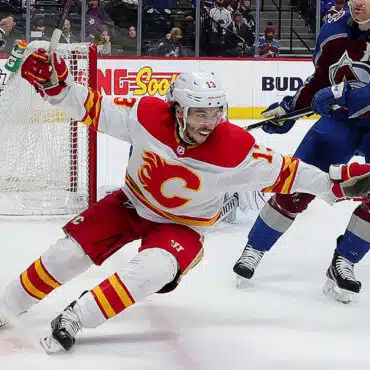 Ice hockey player in white and red uniform skating fast on the rink.