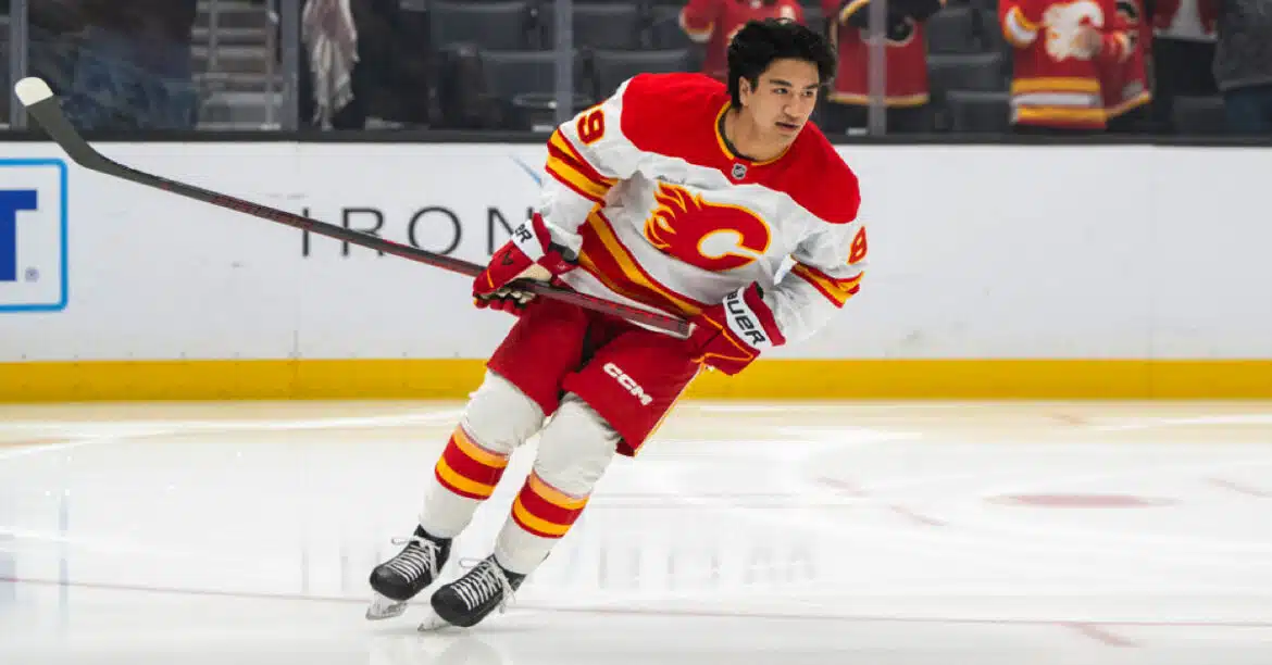 Ice hockey player in red and white Calgary Flames uniform skating on ice.