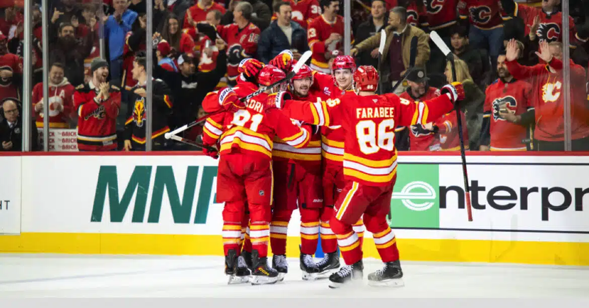 Hockey players in red uniforms celebrating a goal on ice.
