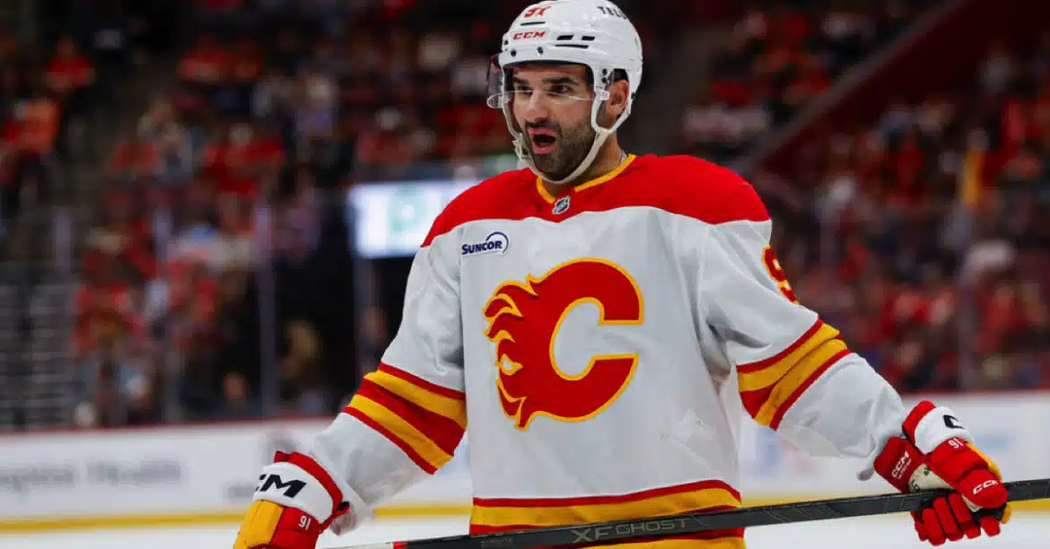 Hockey player wearing a white Calgary Flames jersey during a game.