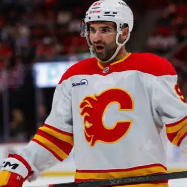 Hockey player wearing a white Calgary Flames jersey during a game.