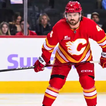 Hockey player in red Calgary Flames uniform on ice rink.