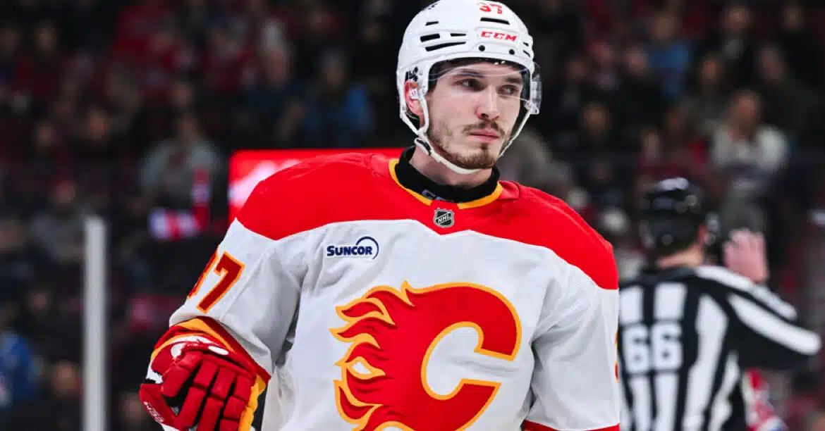 Calgary Flames hockey player in white and red jersey on ice rink.