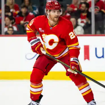 Hockey player in red Calgary Flames uniform skating on ice.