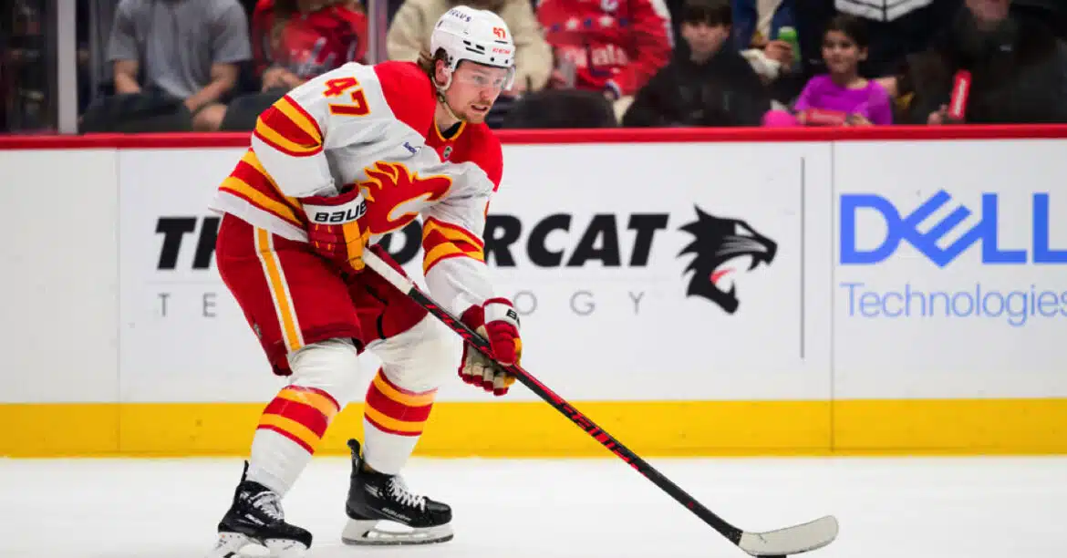 Hockey player in Calgary Flames uniform handling the puck on ice.