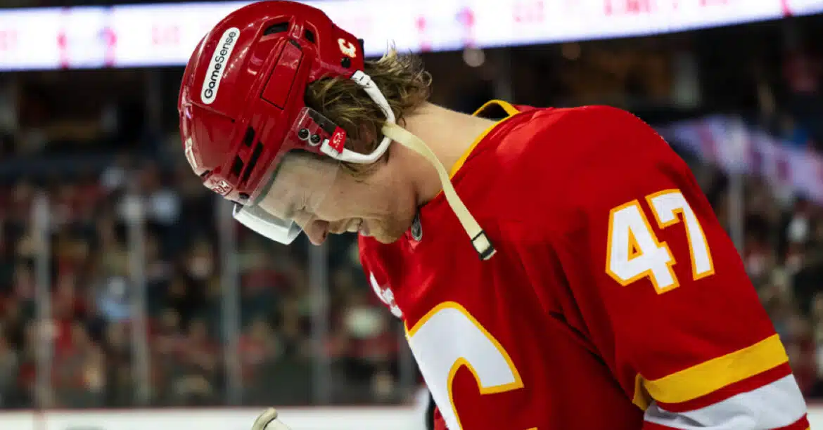 Hockey player in red jersey looking down thoughtfully on the ice.
