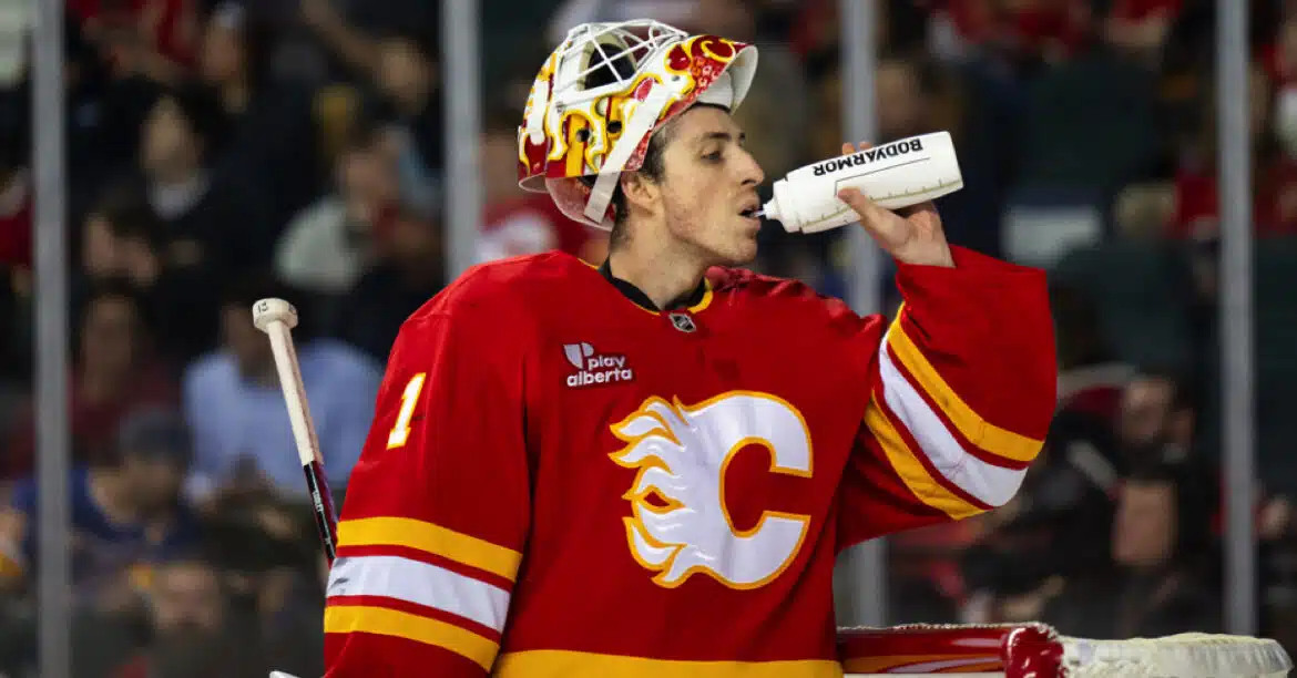 Hockey player in Calgary Flames uniform drinking water during a game.
