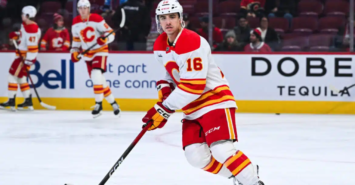 Hockey player in red and yellow uniform skating on ice with a stick.